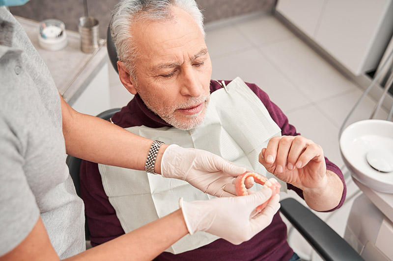 older man looking at his new dentures