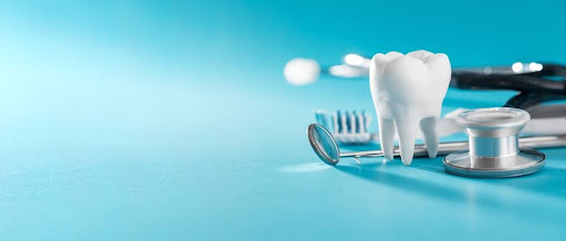 Model tooth beside dental tools and a stethoscope on a blue background