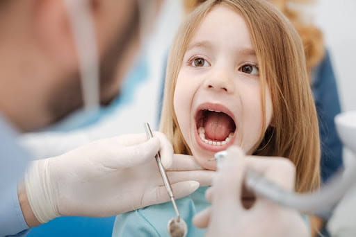 Young girl opening wide for a dental checkup with her dentist